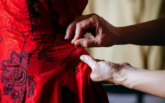 Close-up of woman's hands sewing with needle. 
