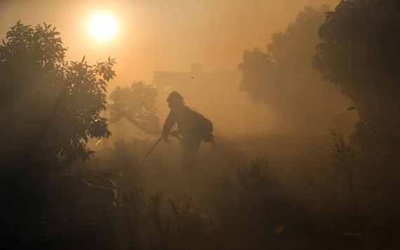 A firefighter pulls a water hose as a wildfires continues to burn Tuesday, Dec. 5, 2017, in Santa Paula, Calif.