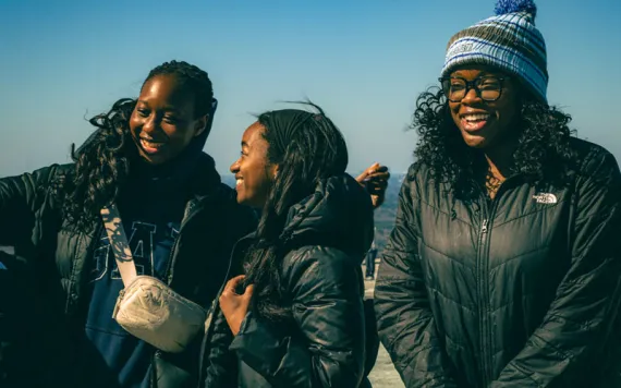 Three students huddled together atop Stone Mountain