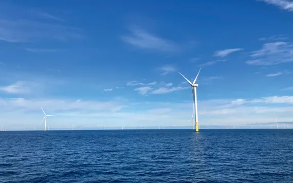 Wind turbines poke out of blue ocean water at the South Fork Wind farm.