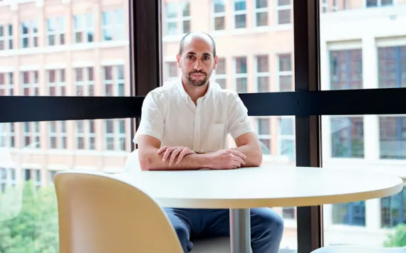 Joe Halso sits at a round table in an office building and looks directly at the camera.