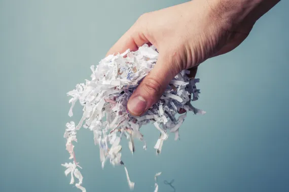 A hand holds shredded paper that can be composted.