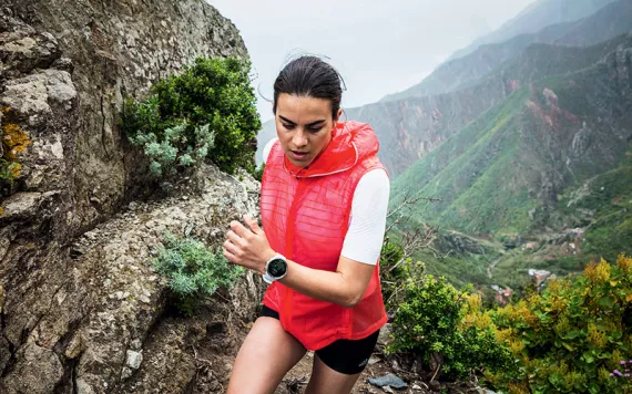 A woman runs along a cliff with a Suunto watch on her left wrist