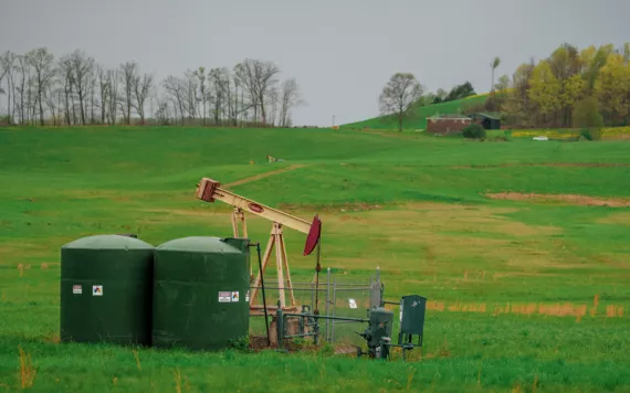 A gas well sits in a big green field.
