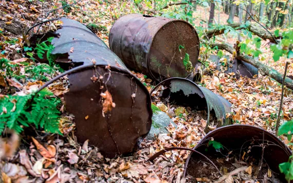 Several rusty remnants of metal barrels lie in a wooded area in Michigan.