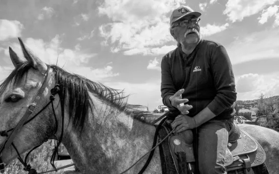 Willie Grayeyes, wearing a ballcap and riding a horse