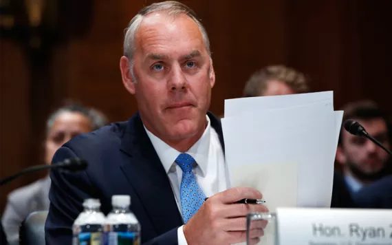Secretary of the Interior Ryan Zinke holding papers during a hearing.