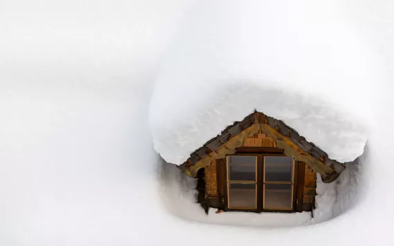 Image of gabled roof peeking out of snow-covered roof