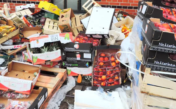 Food waste and boxes piled beside a brick wall