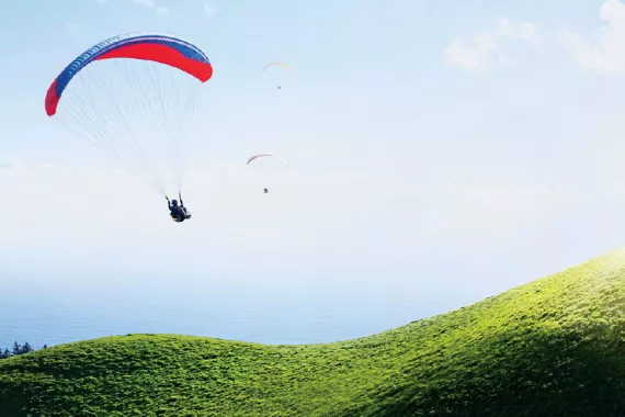 Three paragliders descend along the curvy flanks of Mt. Tamalpais in Marin County, California, overlooking the Pacific Ocean. 