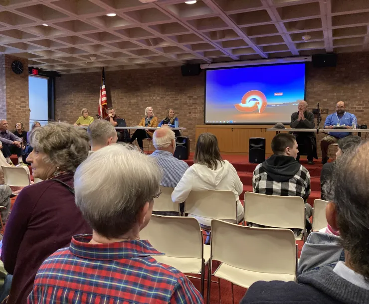 A panel of people in a library. The photo is taken from the audience who are all seated.