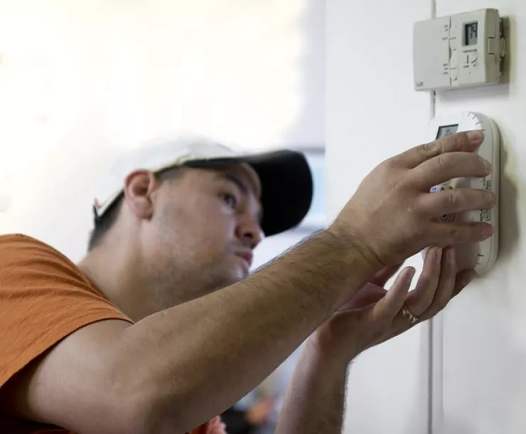 Man installing a programmable thermostat in a home.