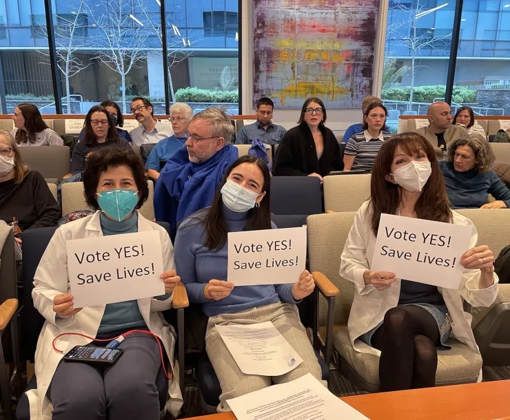 Supporters of amendments to rules 9-4 and 9-6 hold signs at the 3/15 BAAQMD board meeting