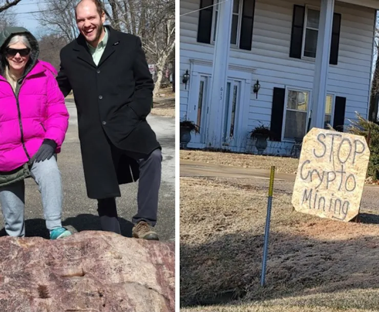 Man and woman on McClouth rock in the road, stop cryptomining protest sign in front of house
