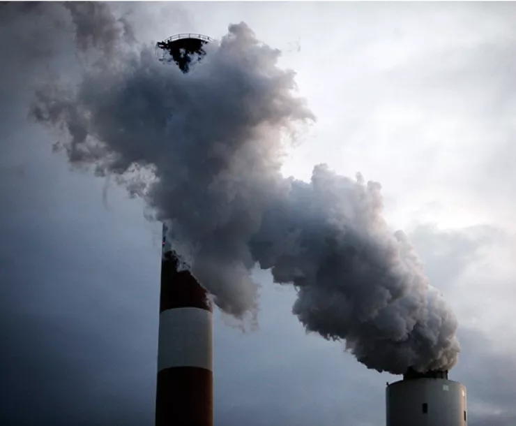 Smokestacks and smoke against gray clouds