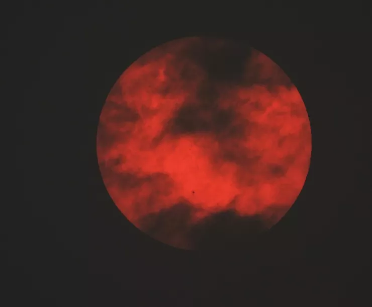 The sun obscured by clouds and filtered by smoke from a wildfire in Canada, photo taken in NYC. The sun is a very strong red color.