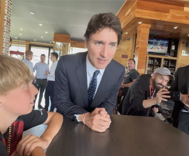 Canadian Prime Minister Justin Trudeau stops a moment to speak with La Coalition Rail Safety Campaign member's son, Carl Zarling, in the rebuilt Music Cafe following mass as Trudeau attends Lac-Mégantic's 10th Anniversary Memorial March.