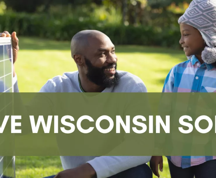 Picture of a Black man showing a young girl a solar panel with the text "Save Wisconsin Solar" over it