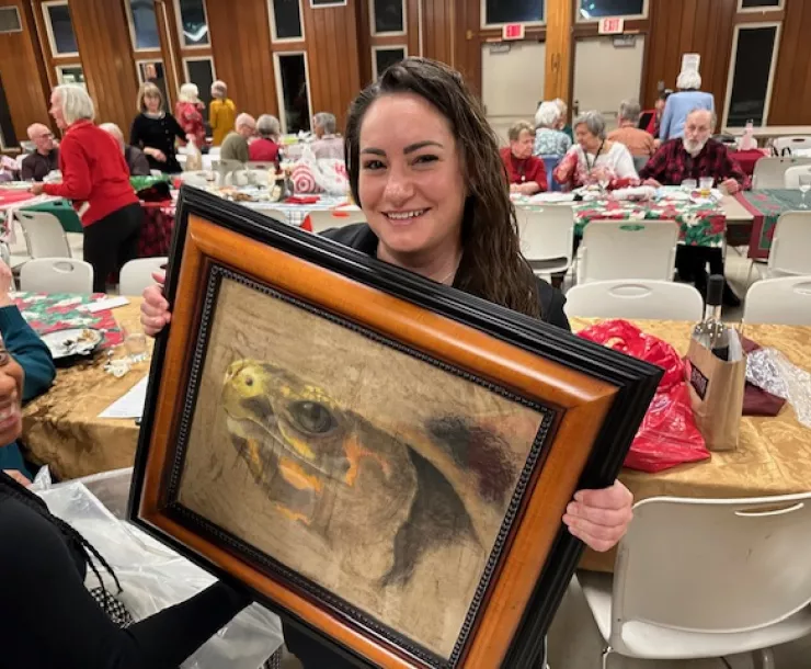 Maria Chilbert holds turtle art she bid on