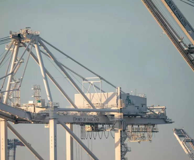 Port of Oakland cranes against pale blue sky
