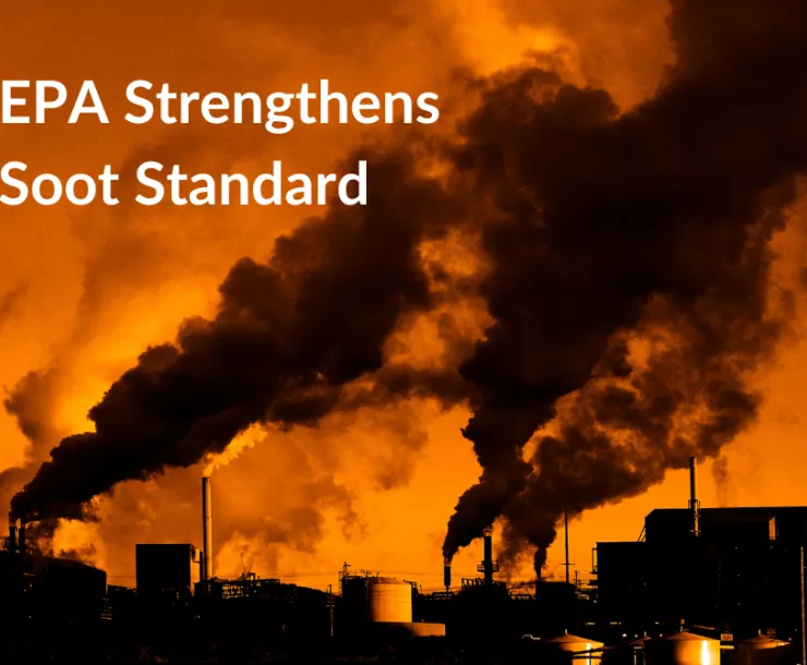 Several smokestacks spew plumes of dark pollution against the backdrop of a red sky.