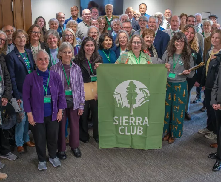 smiling attendees pose in front of green Sierra Club sign at Conservation Education Day
