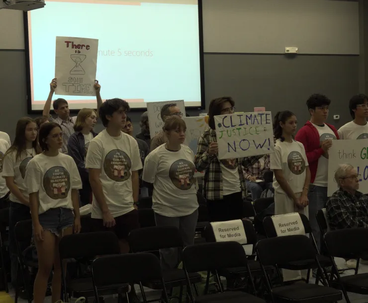 a group of young activists in white t-shirts holding signs
