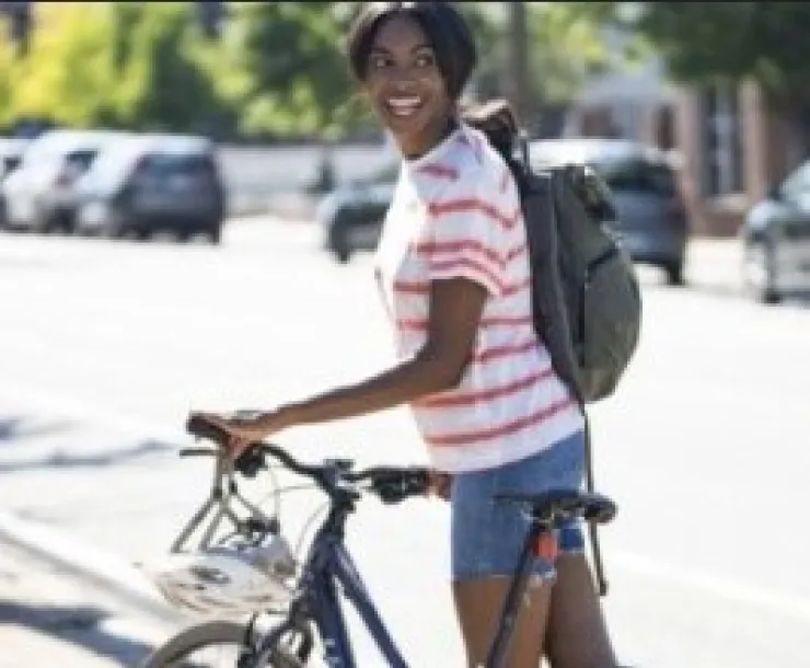 A person in a white and pink shirt walks bike down a road. Photo (first page) by Brian O'Doherty. Photo by Genya O'Neall for The Luupe