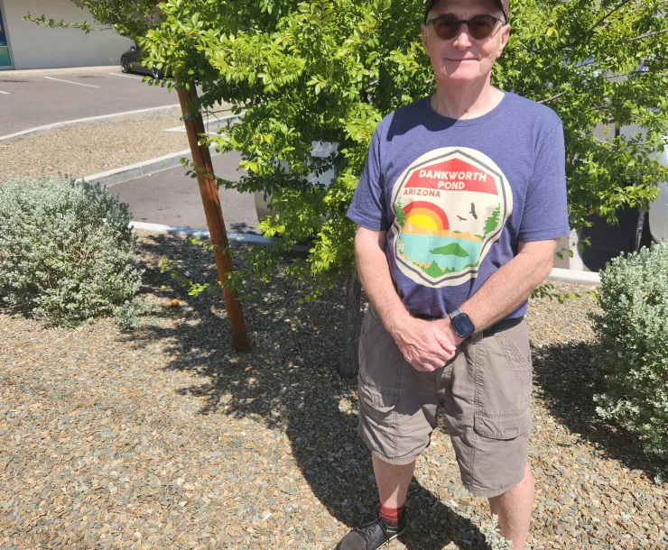 a person in a hat and sunglasses standing next to a tree