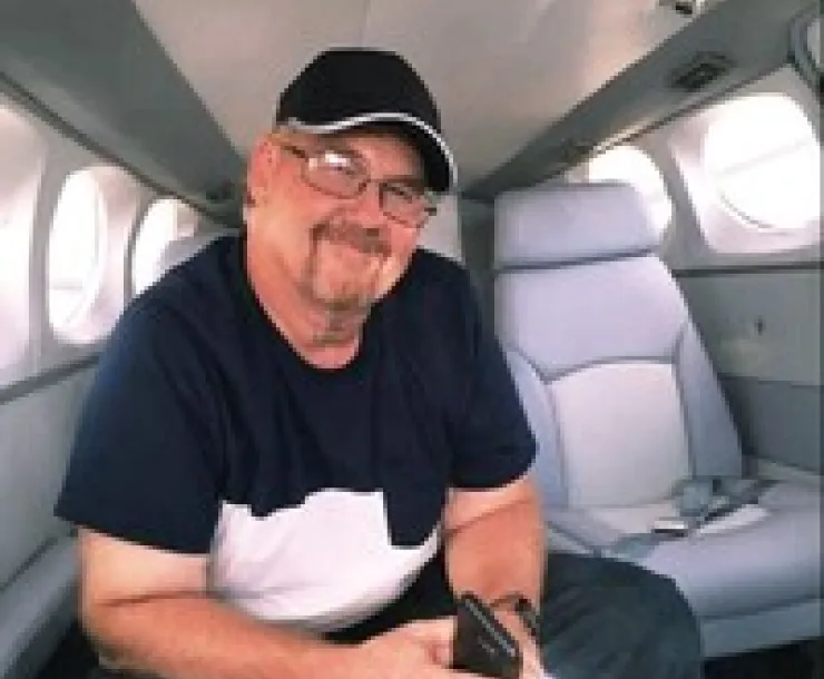 white man wearing glasses in black T-shirt and black seed cap