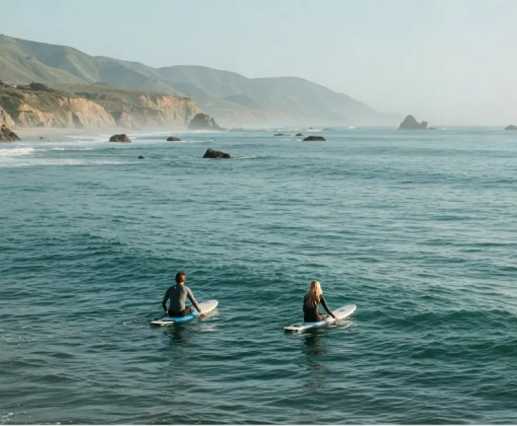 Two surf-boarders in the ocean, waiting to catch a wave