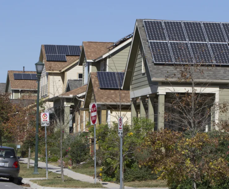 picture of multiple houses with rooftop solar on top on a street
