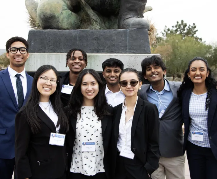 a group of young people poses next to a statue