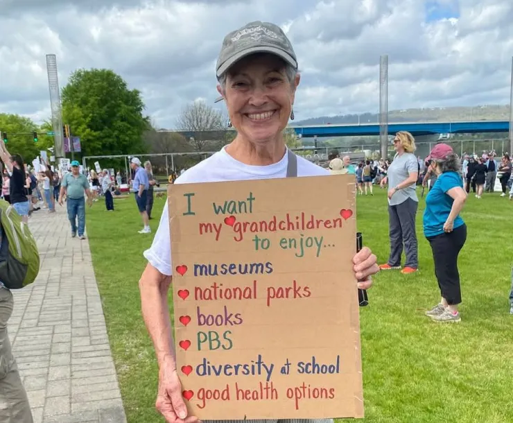 Lady smiles holding a handmade sign