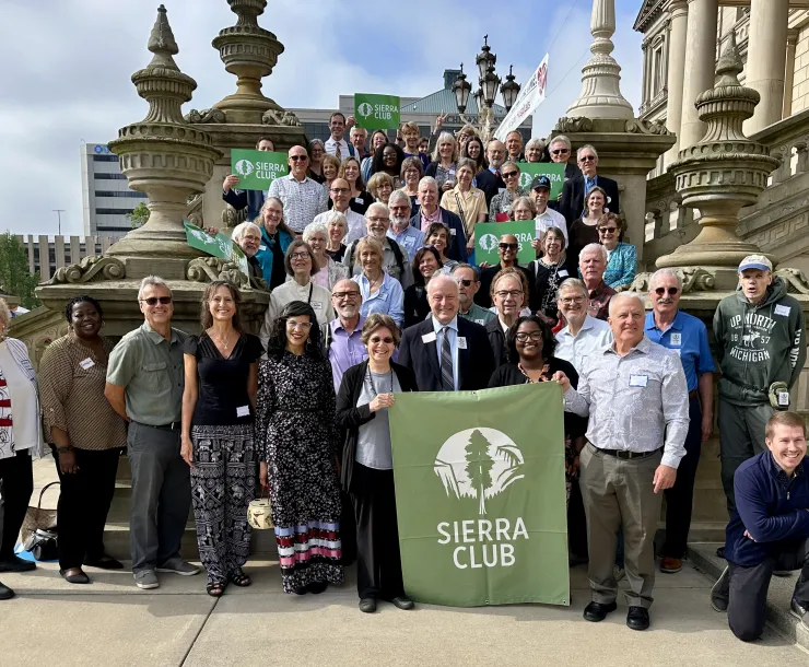 A group of volunteer lobbyists and Sierra Club staff gathered on the Michigan State Capitol steps with a Sierra Club banner and signs.