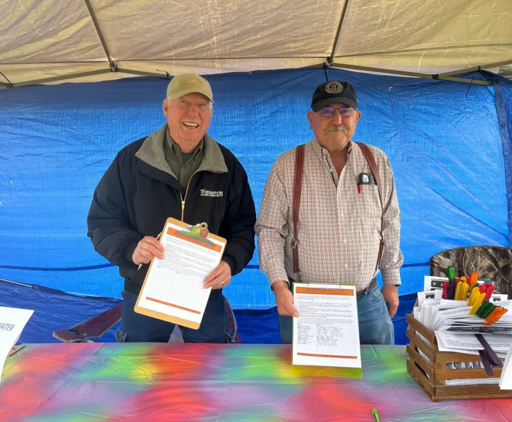 two men in a tent with petitions on clipboards