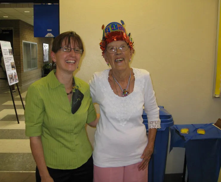 two people standing side by side, one wearing a birthday hat