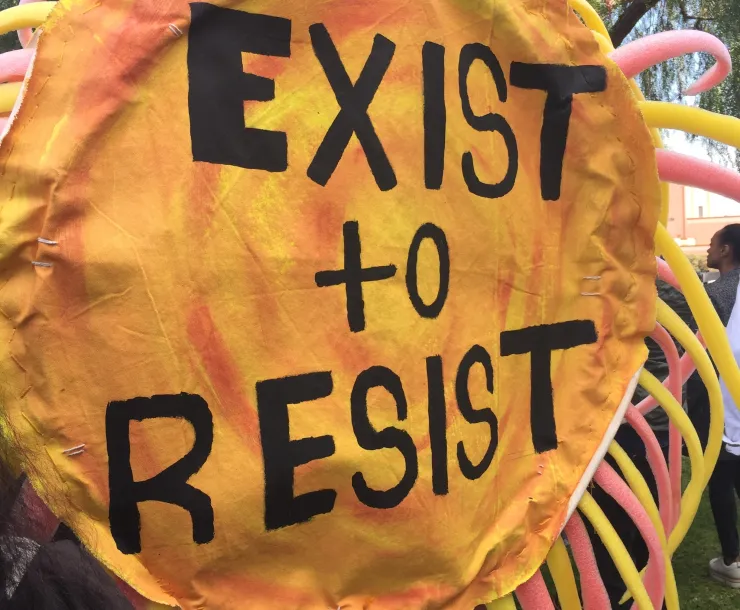 Circular yellow sign says Exist to Resist