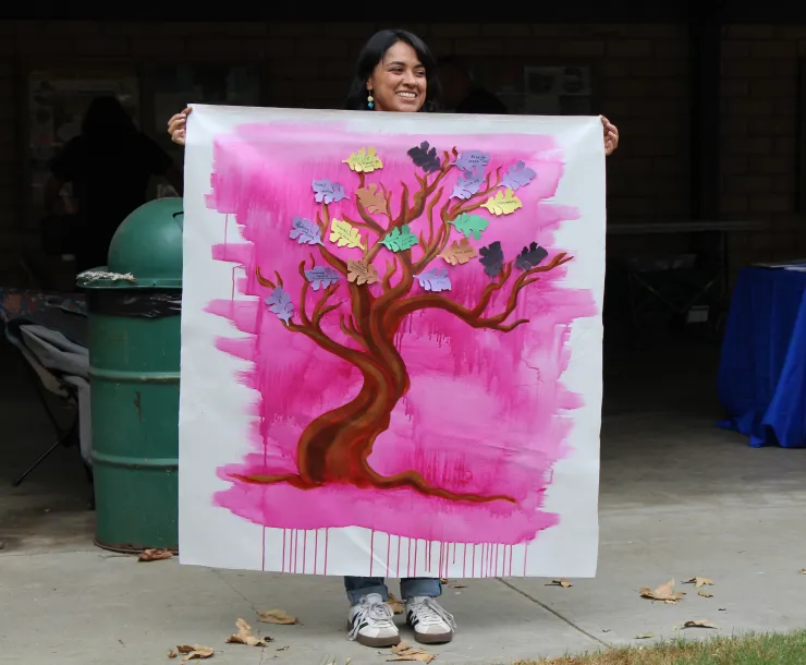 Artist in Residence Kristy Sandoval holds up the community mural