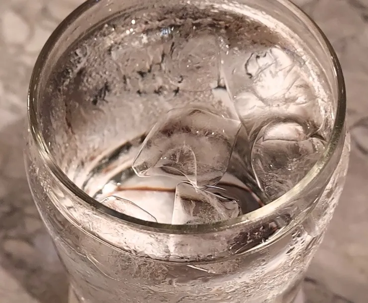 A glass of water on a countertop is seen from above