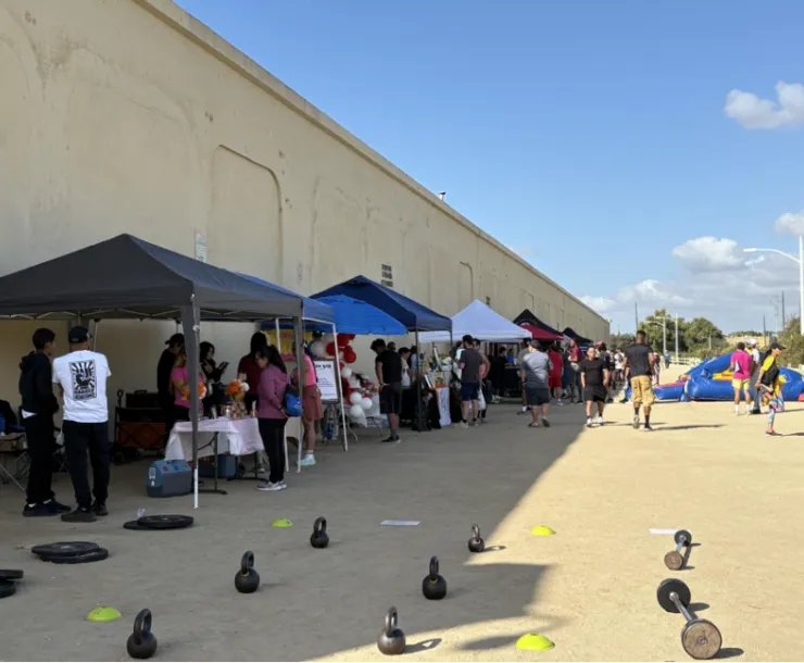 Row of stands with umbrellas, including many dumbbells on the ground