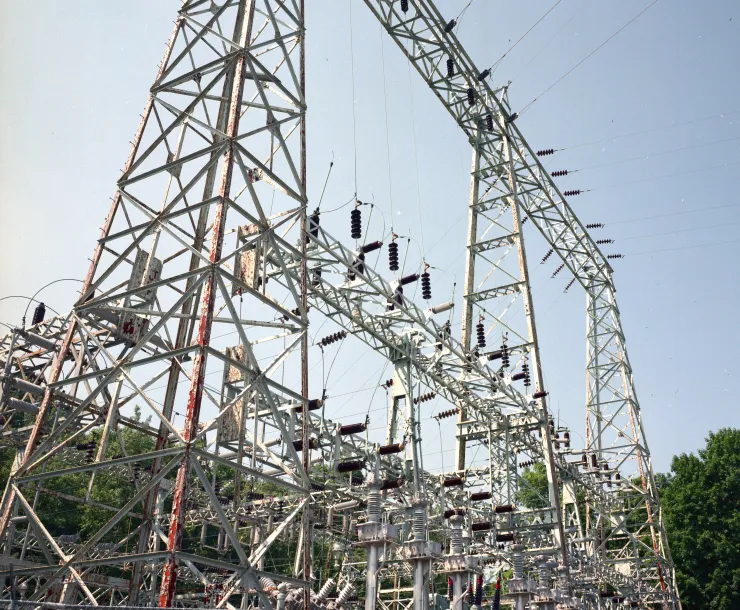 A large electricity station structure with wires silhouetted against the pale blue sky