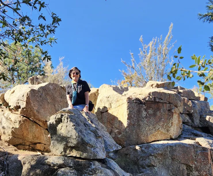 a person poking out behind some large boulders in a rocky area