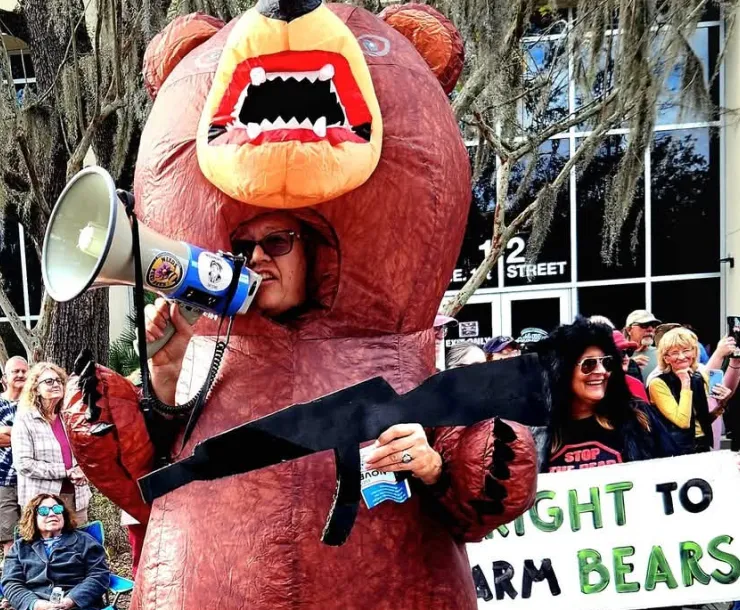 Photo of protesters dressed as Black Bears carrying mock rifles and signs saying Right to Arm Bears