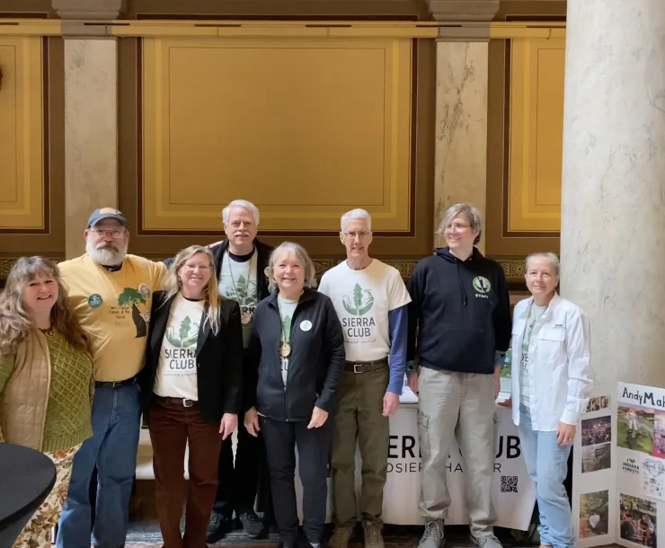 A group of eight people indoors at the Statehouse. Some are wearing white t-shirts with the Sierra Club Hoosier Chapter logo. They are smiling for the photo.