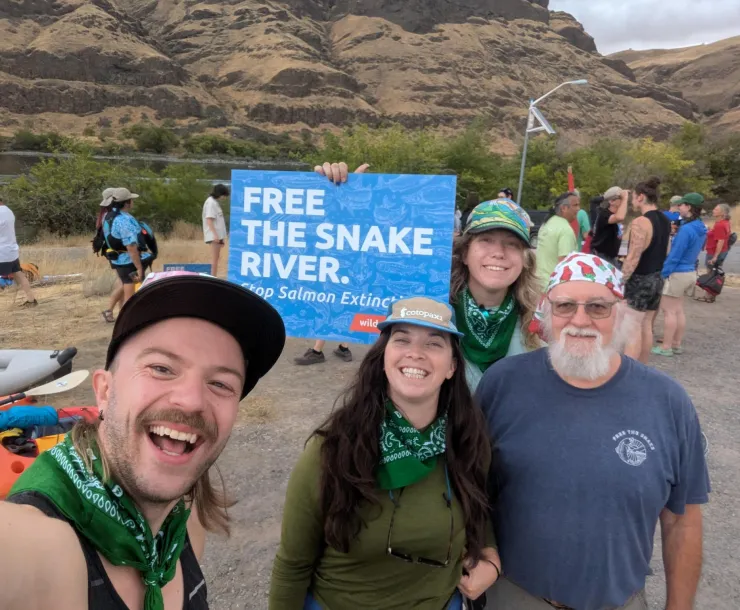 A photo of four people smiling at the camera and holding a sign that reads, Free the Snake River