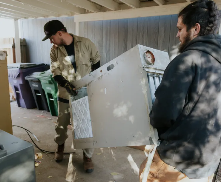 Two people carrying an appliance for a heat pump Installation