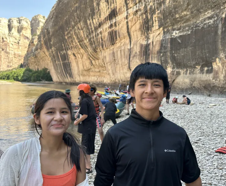 A photo of a teenage girl and boy in front of a river in a canyon 
