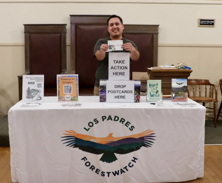 Photo of a man behind a table collecting comments on protecting forests