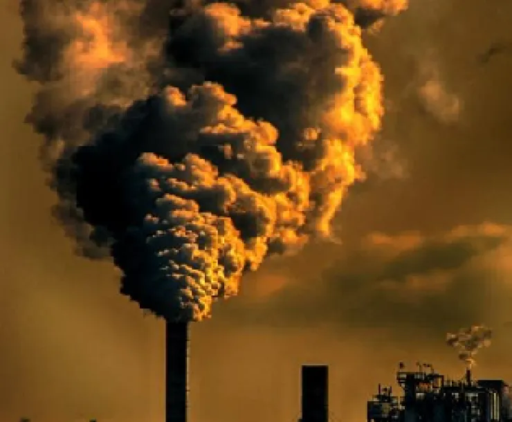 smokestack with smoke billowing with orangish background colors